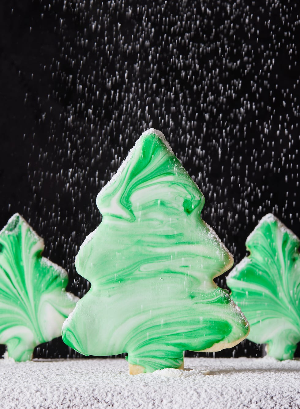 christmas tree cookies decorated with tie dye style green and white swirl icing