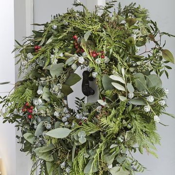 real handmade green wreath on the front of an open white door, staircase in the background