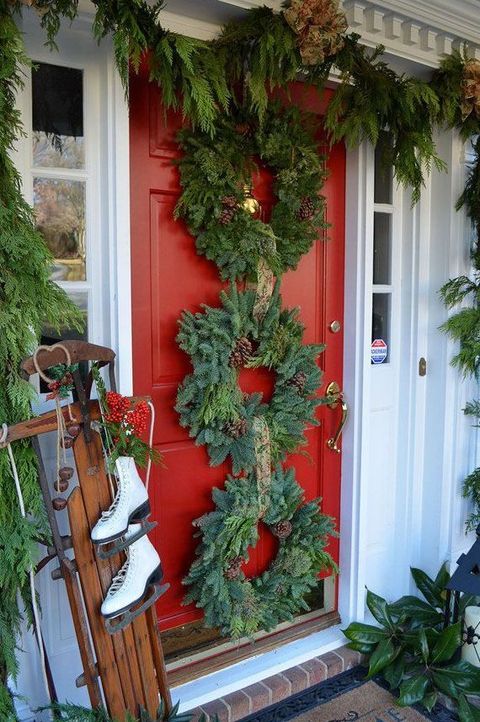 diy christmas wreaths, three evergreen wreaths vertically aligned on a red front door