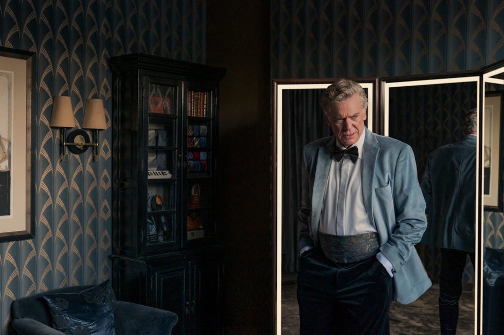 Un hombre vestido con un esmoquin se encuentra en una habitación elegante.