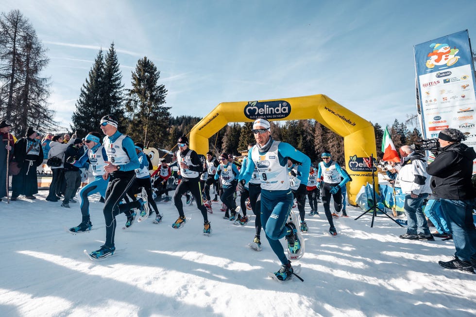 competitors starting a snowshoe race under a branded arch