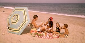 1970s family of four sitting together on ocean seashore by beach umbrella picnicking eating watermelon photo by d corsonclassicstockgetty images