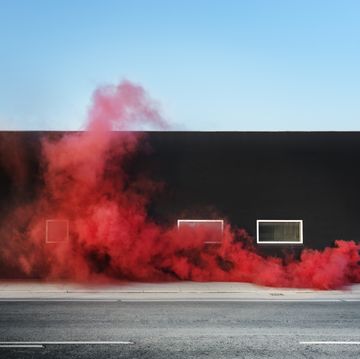 red colored smoke in urban area, shot against a black building