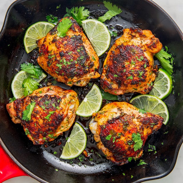 chicken thighs in a skillet with lime slices and cilantro
