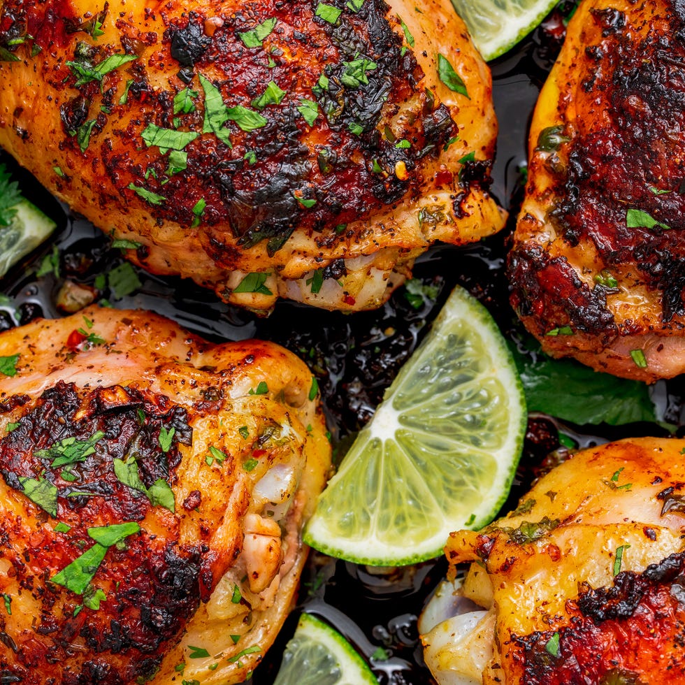 chicken thighs in a skillet with lime slices and cilantro