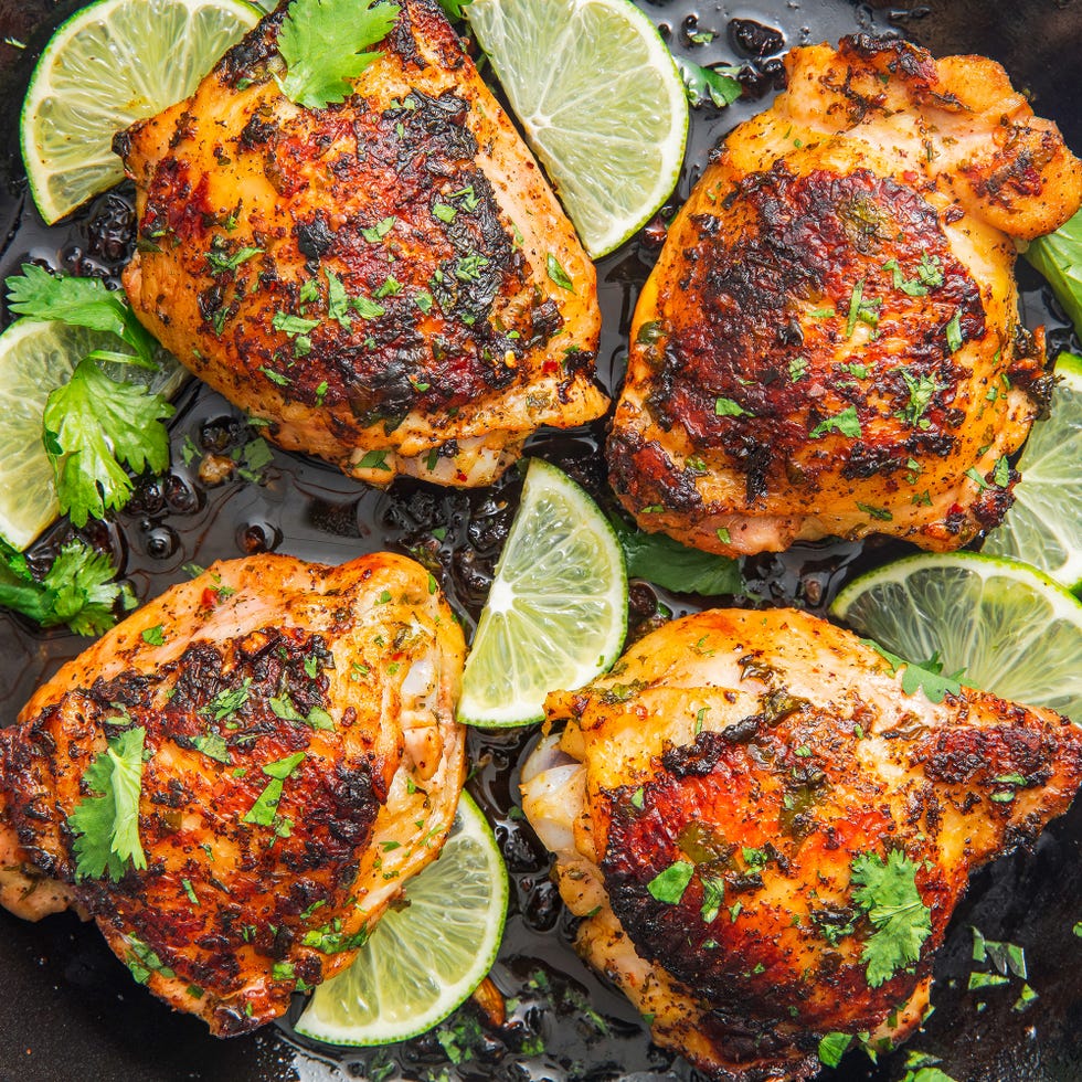 chicken thighs in a skillet with lime slices and cilantro