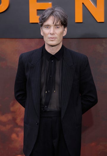 cillian murphy poses for the camera in a black suit and black shirt