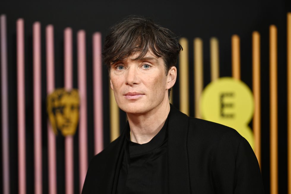 cillian murphy stands in front of a bafta and ee branded background at the bafta film awards