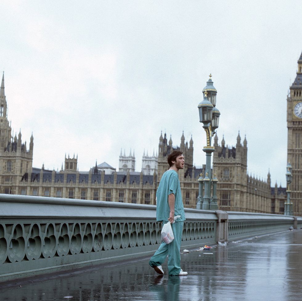 cillian murphy walking along an empty bridge in a film scene