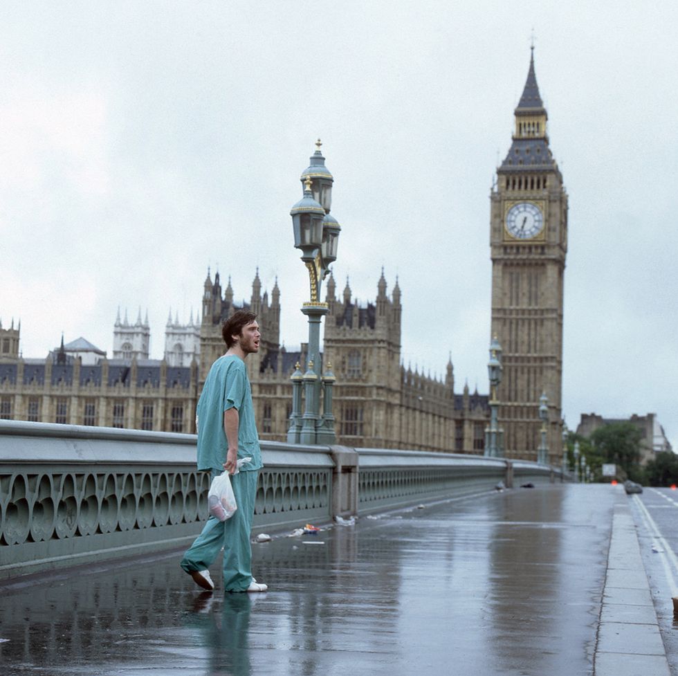 cillian murphy walking along an empty bridge in a film scene