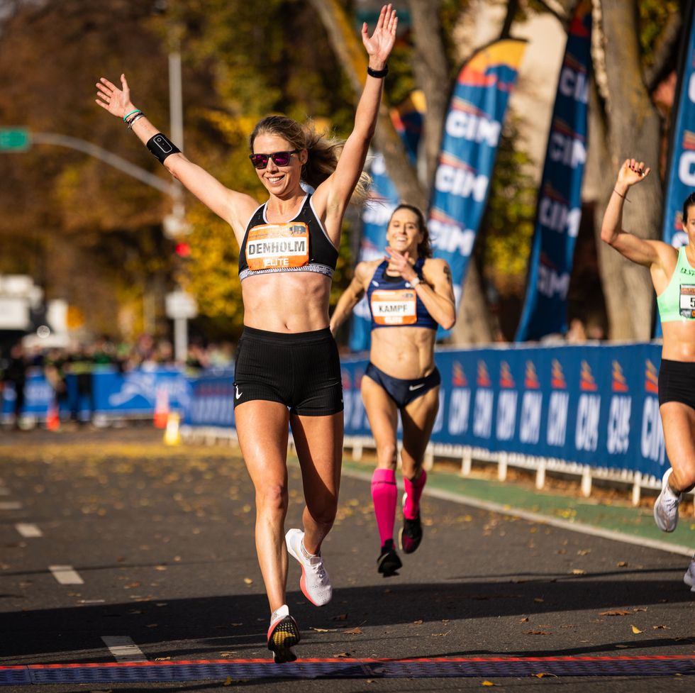 a runner crosses the finish line with her arms raised