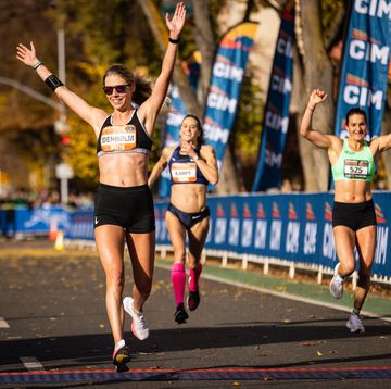 a runner crosses the finish line with her arms raised