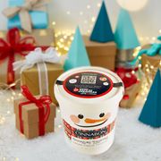 cinnabon signature cream cheese frosting in a snowman themed pint container surrounded by brown gifts with white and red bows
