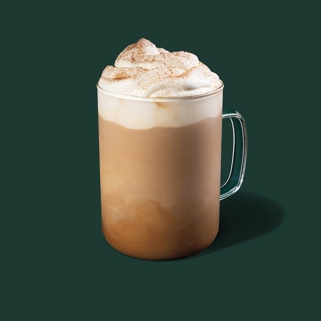 glass mug of layered coffee drink topped with whipped cream and cinnamon