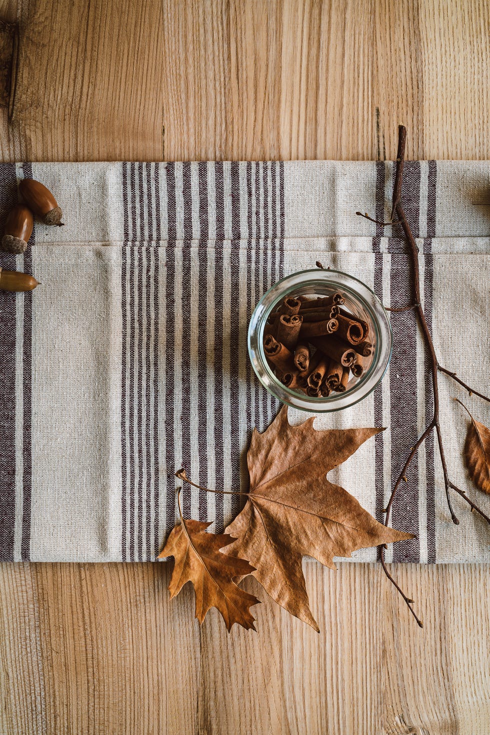 cinnamon sticks in glass jar on linen towel autumn, fall still life
