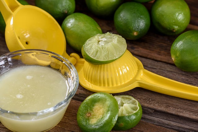 yellow citrus juicer with limes and juice