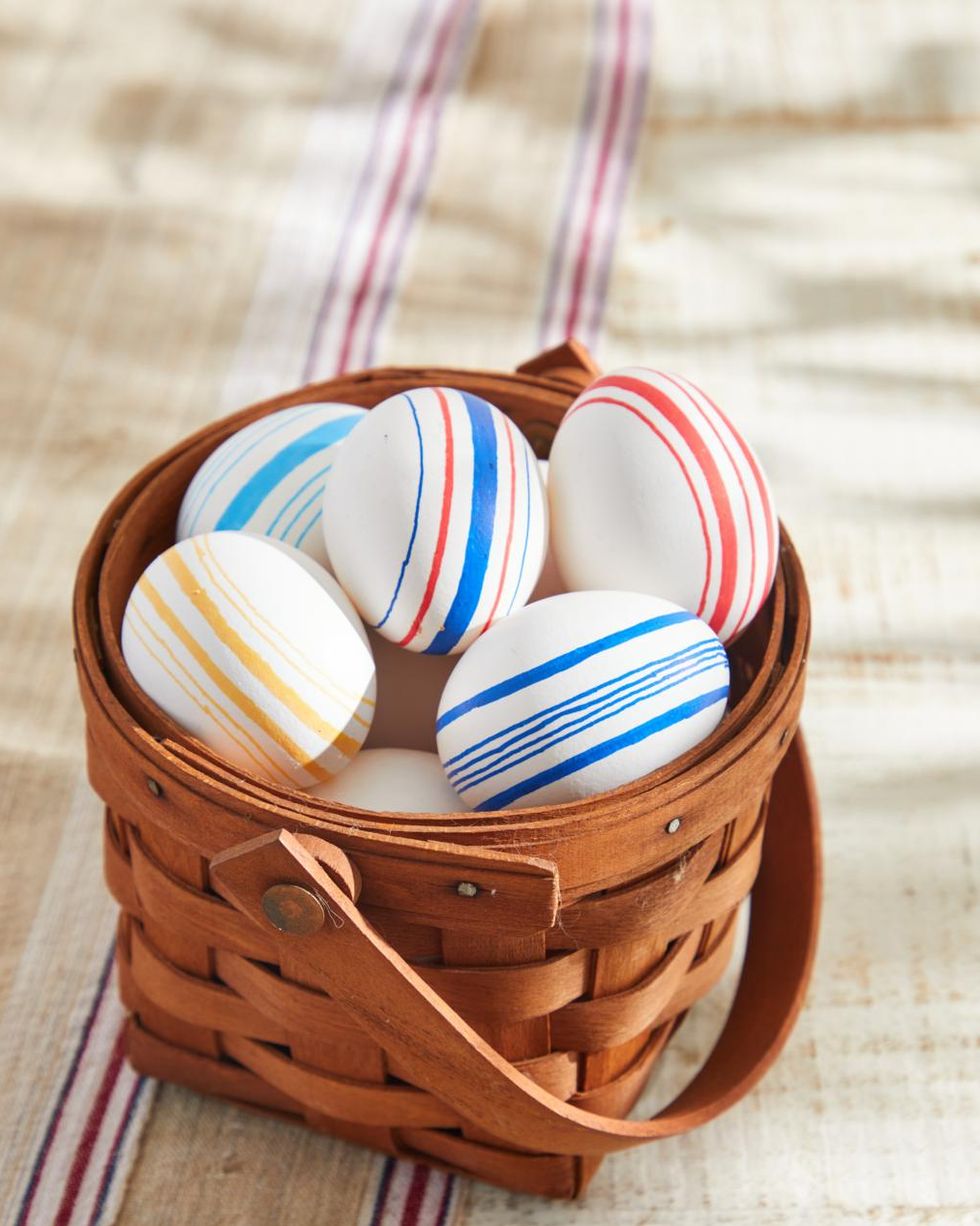 easter eggs decorated to look like vintage grain sack with striped on them set in an easter basket