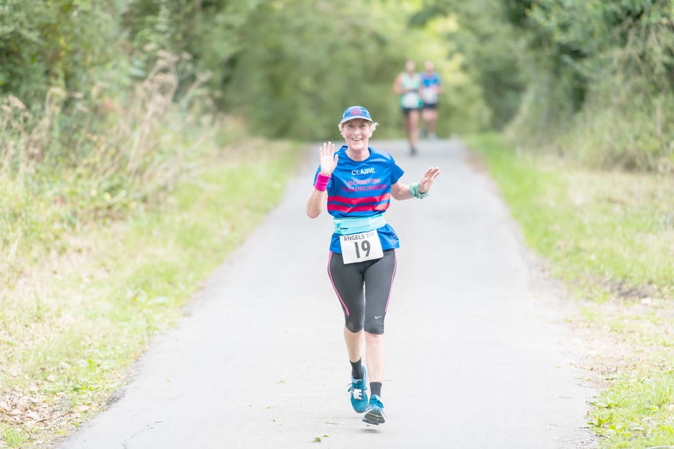 woman waving while running along a rural road