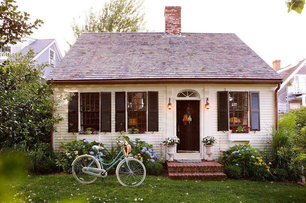 white clapboard cape cottage style home with black shutters