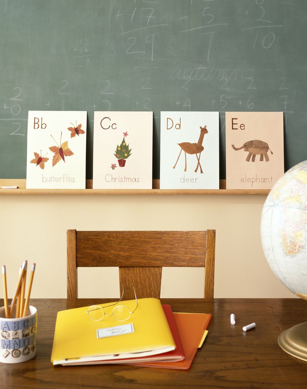 Desk in front of chalkboard with alphabet flash cards on in classroom