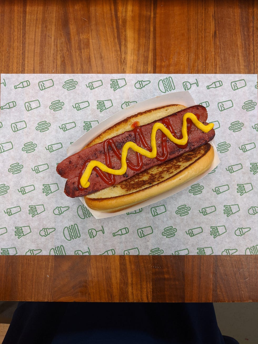 overhead shot of hot dog with split frank drizzled with ketchup and mustard