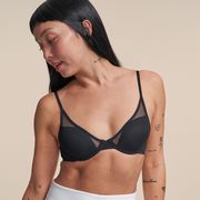 a model stands in front of a taupe backdrop wearing a black pepper bra for small boobs to illustrate a pepper bra review 2022