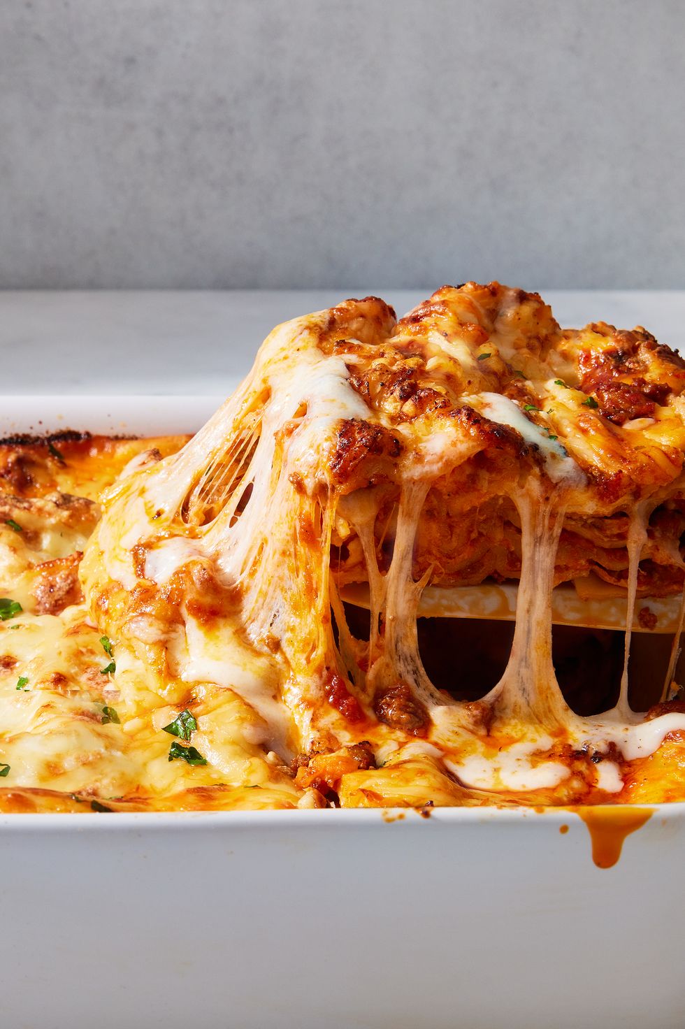 classic lasagna in a white pan topped with fresh herbs