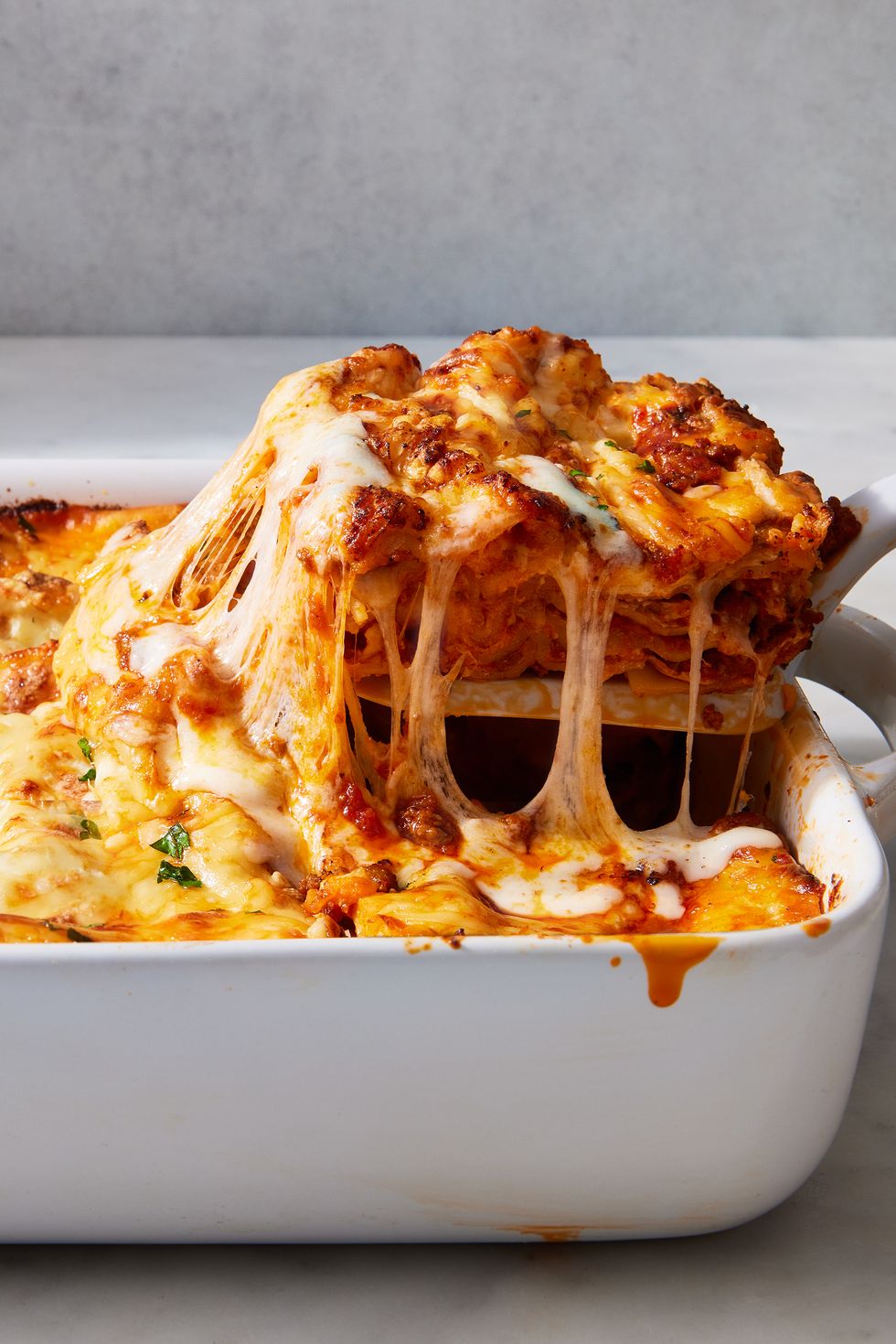 classic lasagna in a white pan topped with fresh herbs