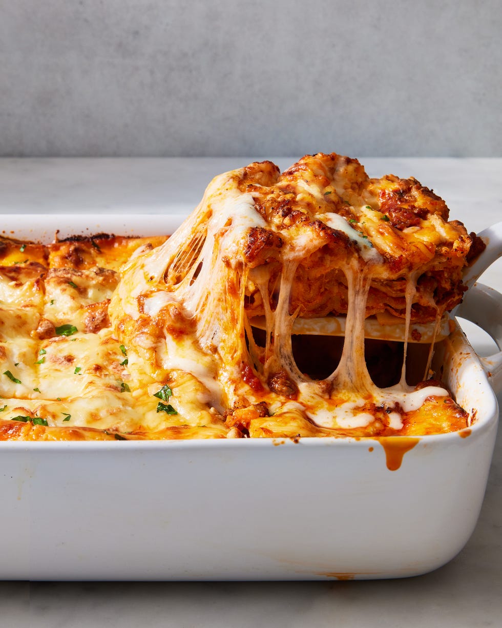 classic lasagna in a white pan topped with fresh herbs