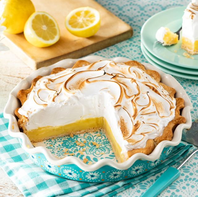 classic lemon meringue pie with slice cut out and lemon slices