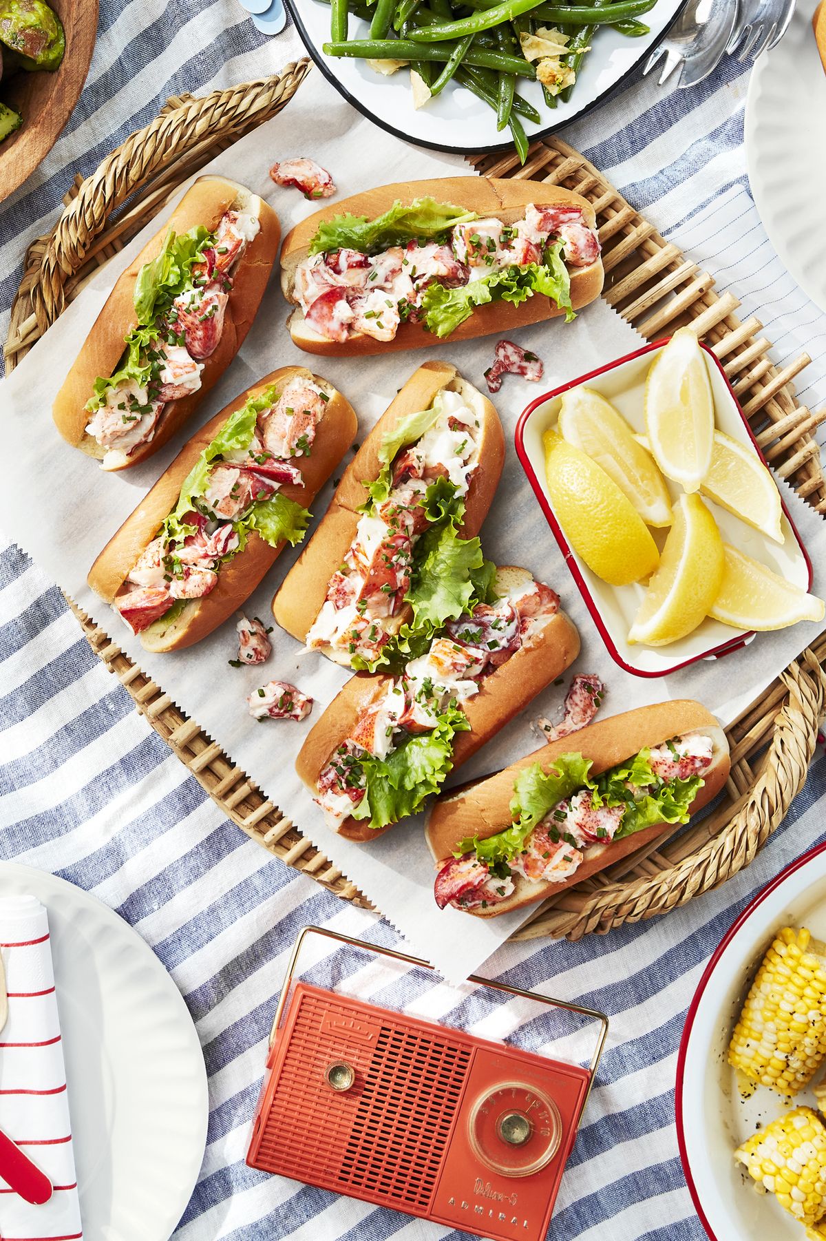 six lobster rolls on parchment paper on a woven tray, a dish you might eat in the summer for a fun activity