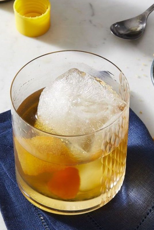 old fashioned drink with a giant ice cube and zest of an orange