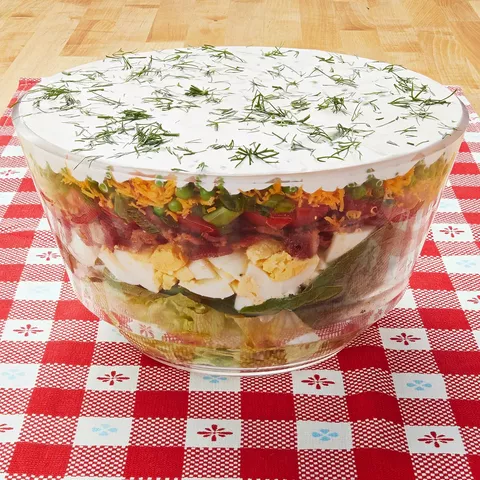 layered salad in glass bowl with red and white linen