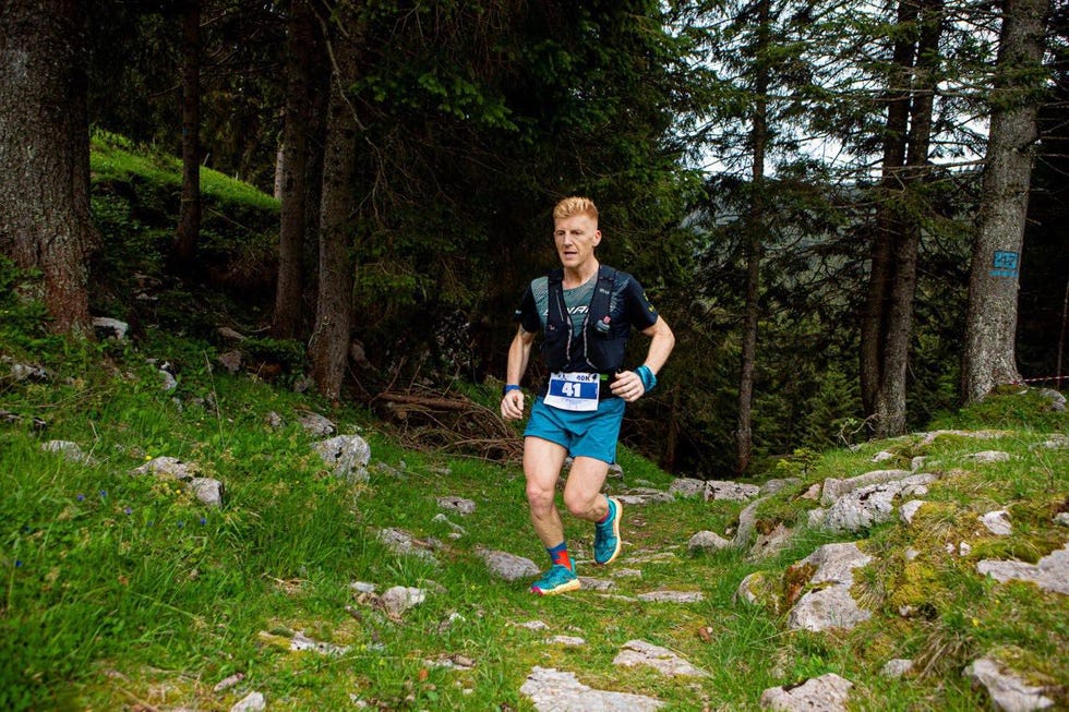 a runner competing in a trail running event amidst forest terrain