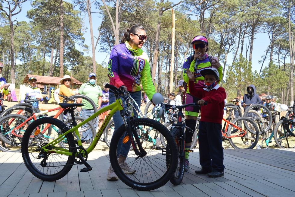 claudia juarez giving a bike to a youth cyclist