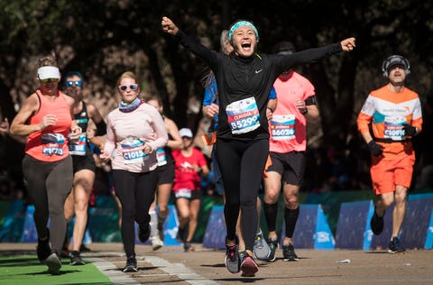 a runner raises her arms to celebrate as she crosses the finish line