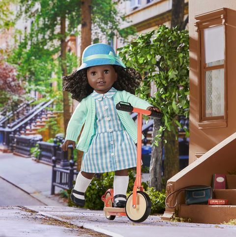 an american girl doll rides a scooter on a city block