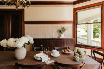 a dining room table with a vase of flowers and a bottle of wine