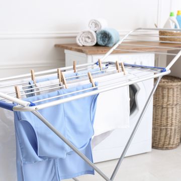 clean laundry hanging on drying rack indoors
