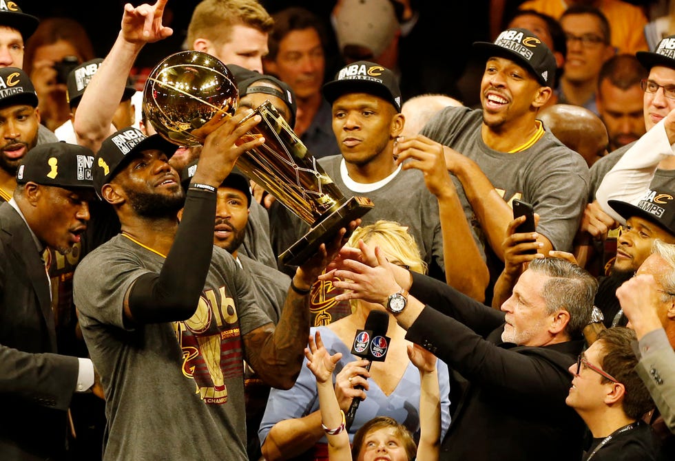 lebron james holding the nba championship trophy as his teammates surround him