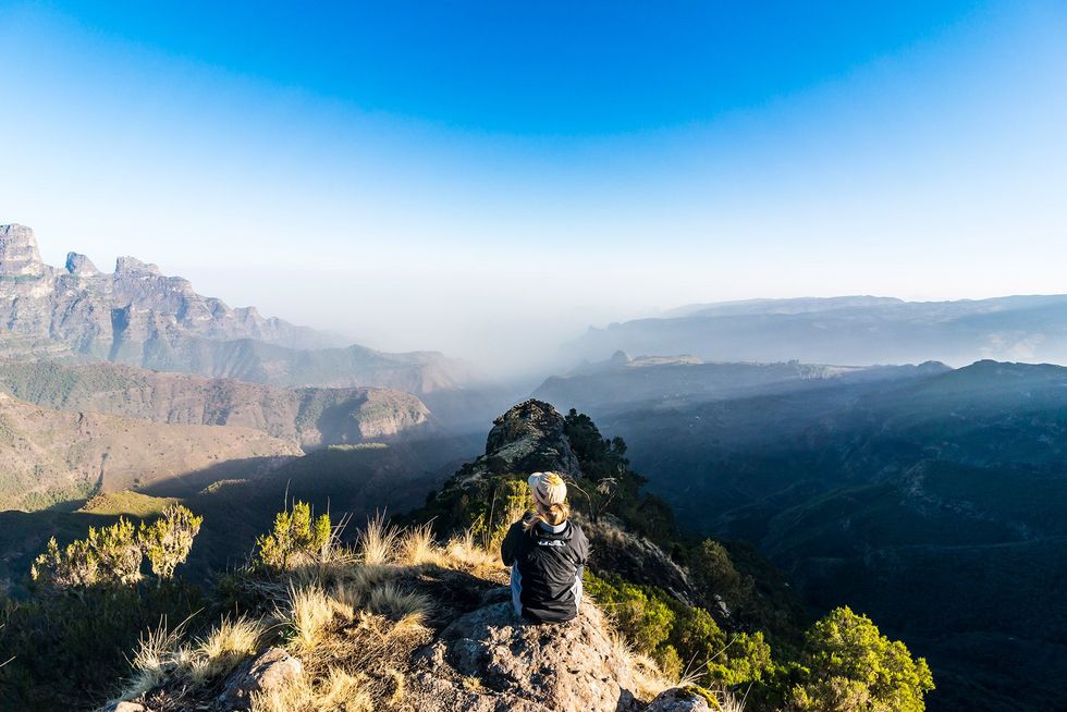 Toeristen laten bucketlists links liggen en gaan op zoek naar echte ervaringen Hier bewondert een vrouw de zonsopgang boven de bergtoppen van het Simien Mountains National Park een Unescowerelderfgoed in Ethiopi
