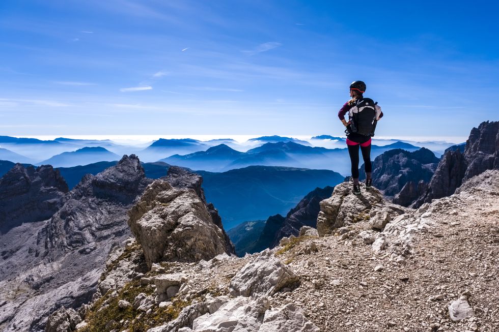 a climber is looking at silhouettes of valleys and mountains...