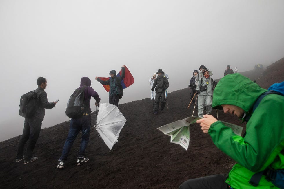 Niet afgeschrikt door het slechte weer trekken klimmers langzaam naar de top terwijl anderen aan de afdaling beginnen