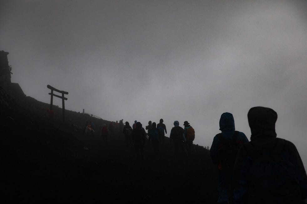 Klimmers steken af tegen de achtergrond van de in mist gehulde flanken van de berg Fuji