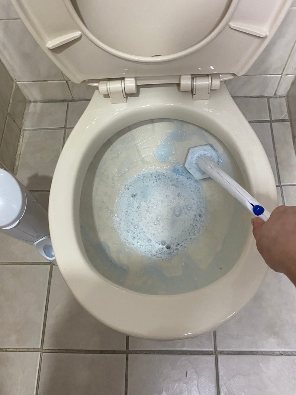 clorox toiletwand being used to clean toilet bowl with holder visible to the left