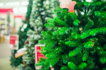 Close up artificial green Christmas trees for sale in the market, shop. Prepearing for Christmas eve, new year party. Selective focus, copy space.