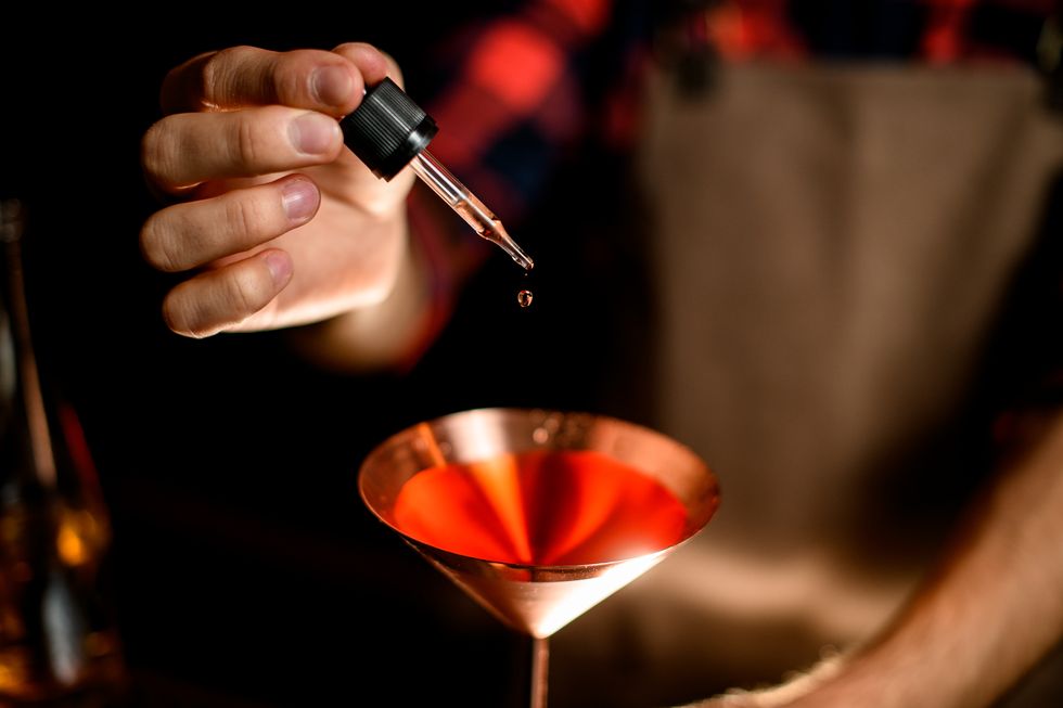 close up. bartender's hand adds cocktail ingredient using dropper