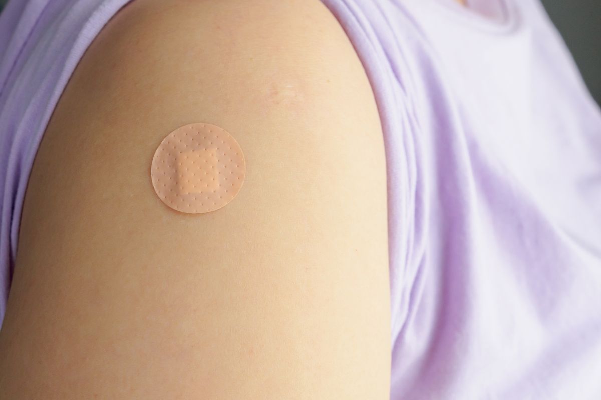 close up circle brown adhesive bandage on patient arm after medicine injection or vaccination