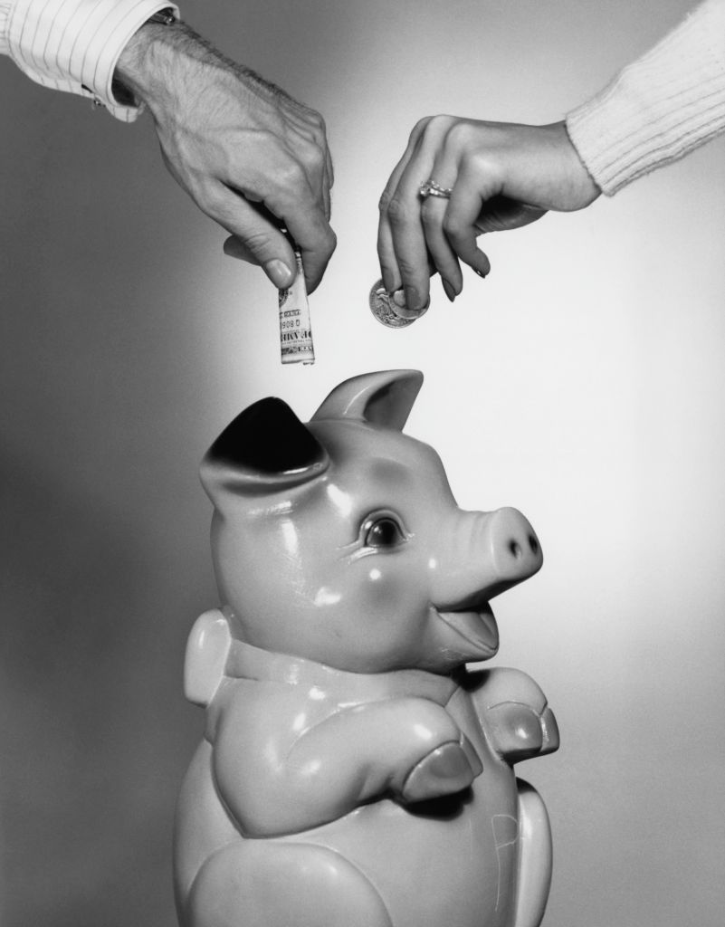close up couple placing money in piggy bank