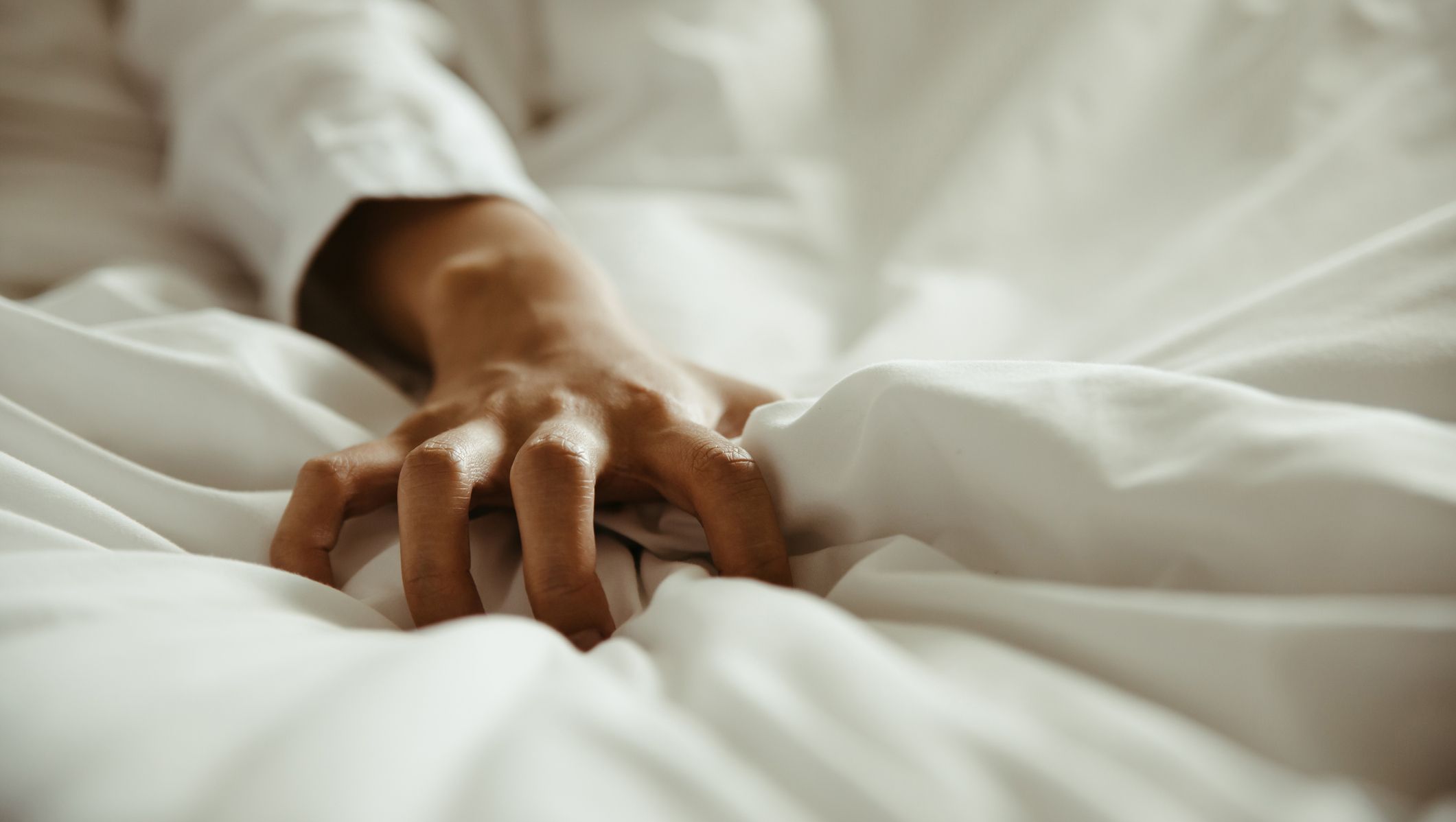 close up hand of female pulling white sheets in ecstasy , feeling and emotion concept